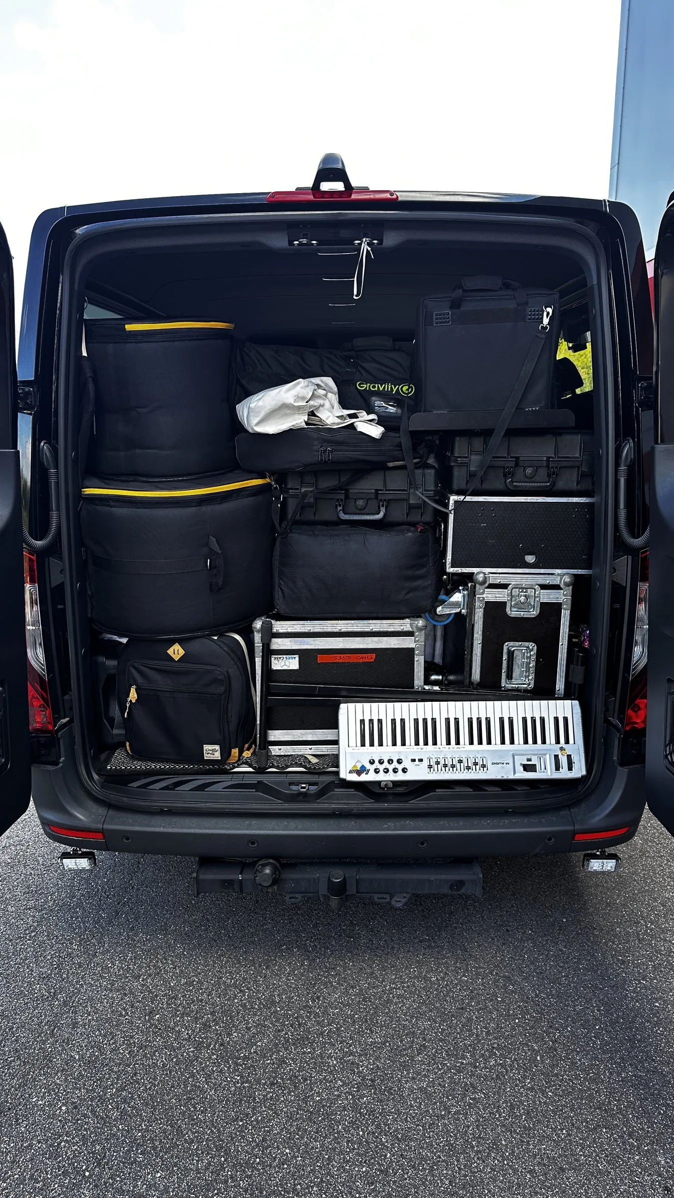 Backline loaded into a SoloTransfer Sprinter — keyboard, flight cases and drum bags