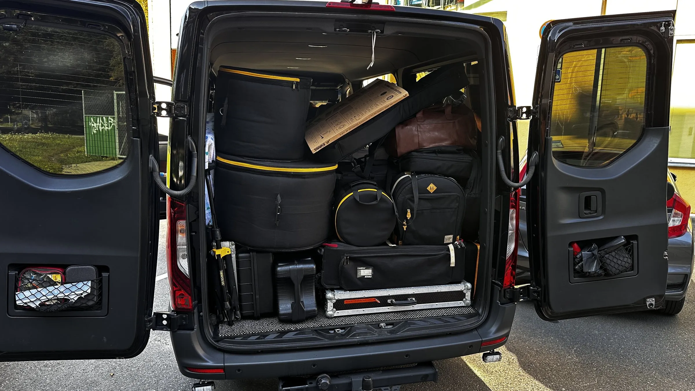 Sprinter rear doors open with touring cases stacked for a venue load-out